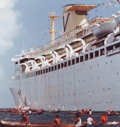 several people in canoes paddling past a large cruise ship