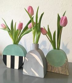 three vases with flowers in them sitting on a table