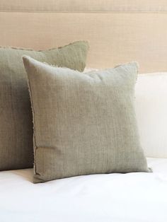 two pillows sitting on top of a bed next to each other