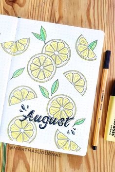 an open notebook with lemons and green leaves on it next to some marker pens