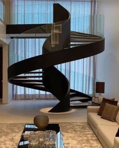 a living room filled with furniture and a spiral staircase next to a glass coffee table