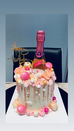 a birthday cake with pink frosting and decorations on the top, next to a bottle of booze