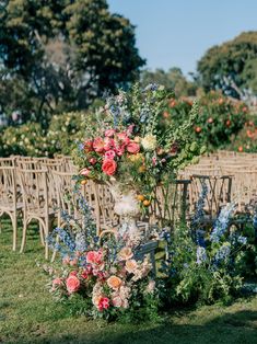 an arrangement of flowers and greenery in front of rows of chairs