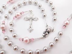 "- Personalized handmade Swarovski crystal rosary beads in gray and light pink. - Choice of medals and letters - Comes with a pouch and gift box This personalized Catholic baby rosary is made with grey and light pink Swarovski pearls and crystals. It makes a perfect baptism, first holy communion, or confirmation gift for a girl! Suitable for ALL AGES. It comes with a personalized name and your choice of sacrament medals. Please read below for details. Over 80 colorful designs to choose from. Ent Catholic Confirmation, Personalized Rosary, Rosary Gift, Pearl Rosary, Pink Swarovski, Confirmation Gifts, Rosary Beads, First Holy Communion, Holy Communion