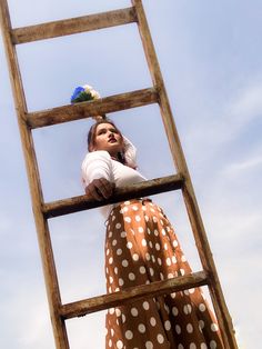 a woman standing on top of a wooden ladder