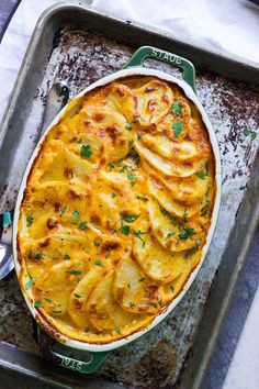 a casserole dish with potatoes and parsley in it on a baking tray