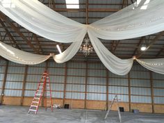 a ladder is standing in front of a white drape draped ceiling with lights on it