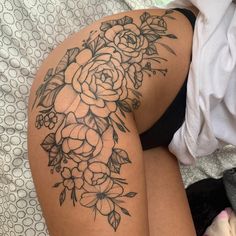 a woman laying on top of a bed covered in lots of black and white flowers