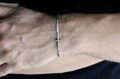 a man's arm with a cross bracelet on it