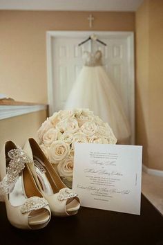 the wedding dress and shoes are sitting on the table next to the card that was placed in front of the bride's bouquet