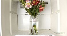 a vase filled with flowers sitting on top of an open refrigerator