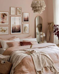 a bedroom with pink walls and pictures on the wall above the bed, along with a wicker basket