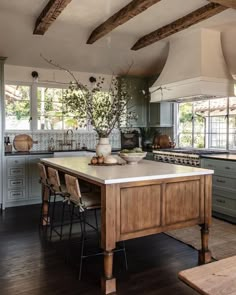 a large kitchen with an island in the middle and wooden beams on the ceiling above it