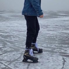 a young man standing on top of an ice covered field with his feet in the air