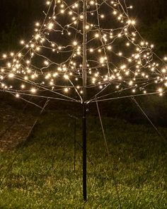 a lighted umbrella in the grass with lights on it's top and bottom part