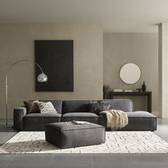 a modern living room with grey couches and white rugs on the floor in front of a gray wall