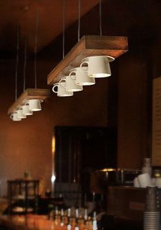 coffee cups are hanging from the ceiling in a restaurant bar with lights above it and below them