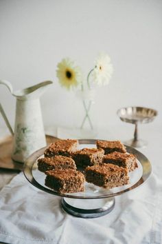 there are pieces of cake sitting on a plate next to a vase with flowers in it