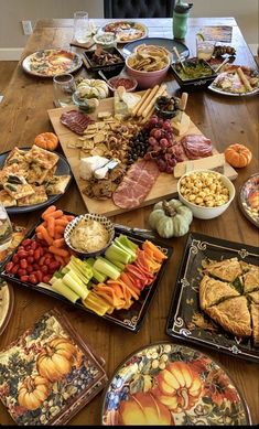 a wooden table topped with lots of plates and trays filled with different types of food