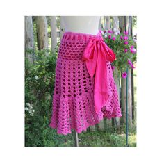 a pink crocheted skirt with a bow on the front and side, in front of some trees