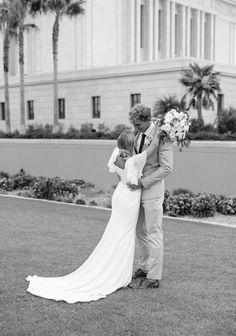 a bride and groom kissing in front of a building