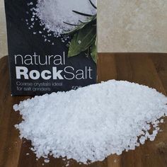 a pile of sea salt sitting on top of a wooden table next to a book