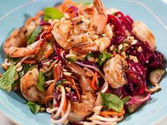 a salad with shrimp, carrots and lettuce in a blue bowl on a table