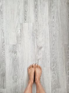 the bare feet of a person standing on a wood floor with white painted planks