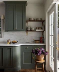 a kitchen with green cabinets and white counter tops