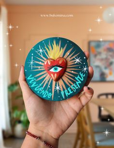 a person holding up a paper plate with a heart on it and an eye painted on the front