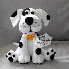 a crocheted stuffed dog sitting on top of a white blanket with black spots