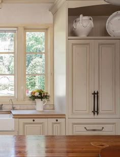 a kitchen with white cabinets and wooden counter tops, along with an island in the middle