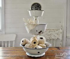 a bowl filled with balls of yarn sitting on top of a wooden table next to a clock