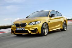 a yellow bmw car driving down a race track