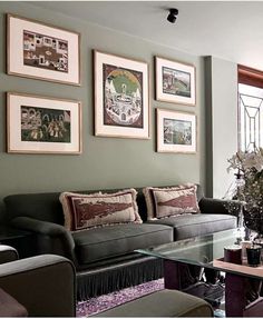 a living room filled with furniture and framed pictures on the wall above it's glass coffee table