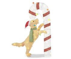 a dog standing next to a giant candy cane with lights on it's side