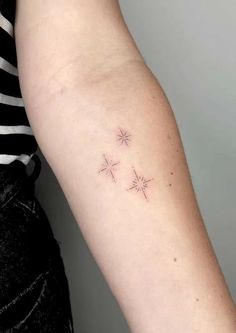 a woman's arm with three small stars tattoo on the left side of her arm