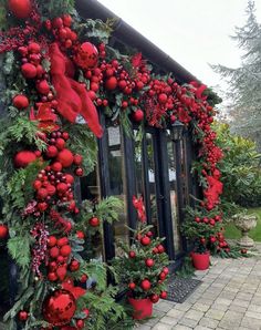 christmas decorations on the side of a building with red balls and greenery hanging from it's sides