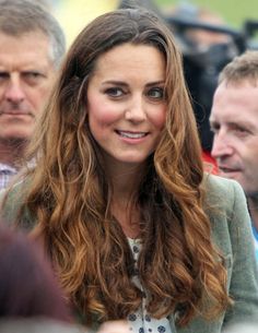 a woman with long brown hair is smiling at the camera while others look on from behind her