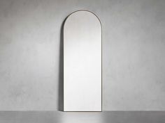 an arch shaped mirror on the wall next to a gray table with a white floor