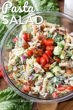 a salad in a glass bowl with tomatoes, lettuce and other toppings