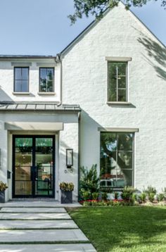 a white brick house with black doors and windows on the front door is shown in this image