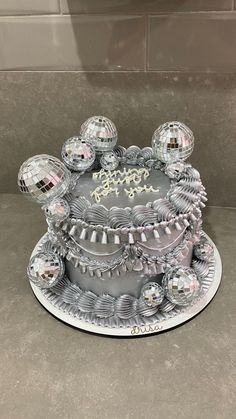 a silver cake with disco balls on top and the words happy birthday written on it