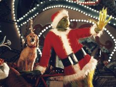 a man dressed as santa clause waves to the crowd in front of christmas decorations and lights