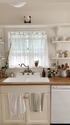 a white kitchen sink sitting under a window next to a dish washer and dryer