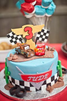 the birthday cake is decorated with cars and race flags on it's top tier