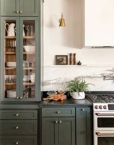 a kitchen with green cabinets and an oven in the center, surrounded by white marble countertops