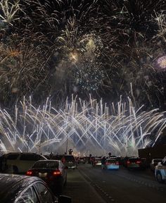 fireworks are lit up in the night sky over cars