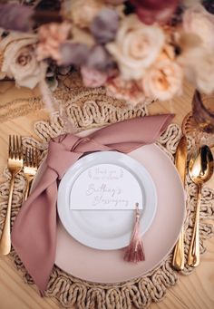 a place setting with pink napkins and silverware