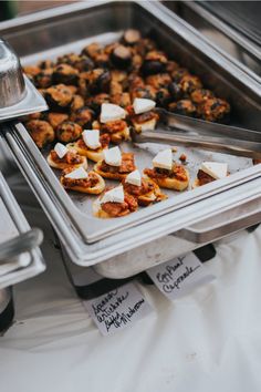 several trays of food are on display for people to eat at the buffet table